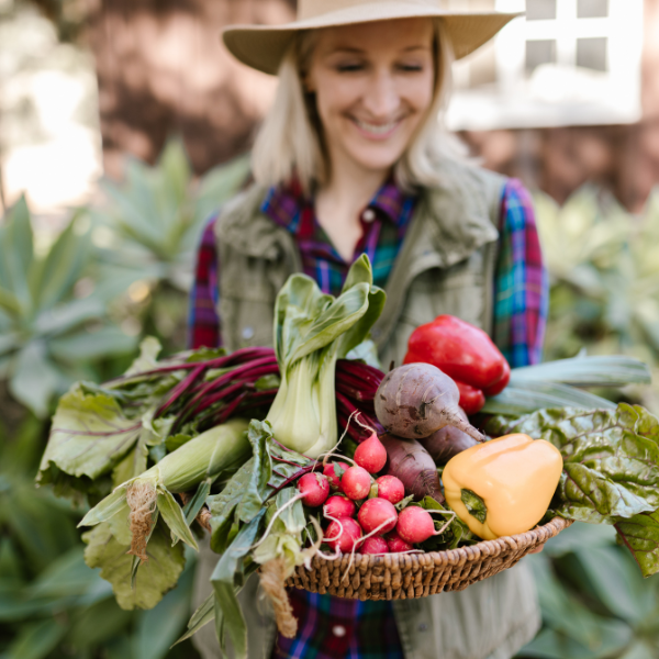 Smiling farmer holding a basket of assorted fresh vegetables, symbolizing organic farming, sustainability, and healthy living