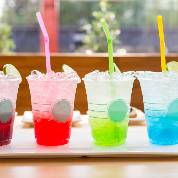 Vibrant iced drinks in takeaway plastic cups with colorful straws, perfect for summer refreshment or beverage product promotion.