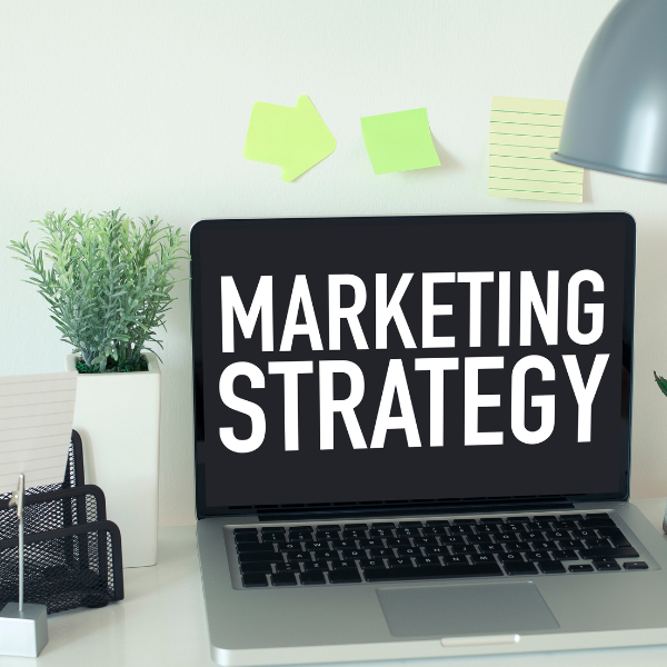 Modern workspace setup with laptop displaying 'Marketing Strategy' text, ideal for digital marketing or business planning content.