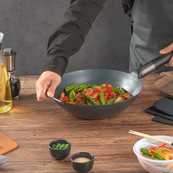 Chef cooking on a black carbon steel wok