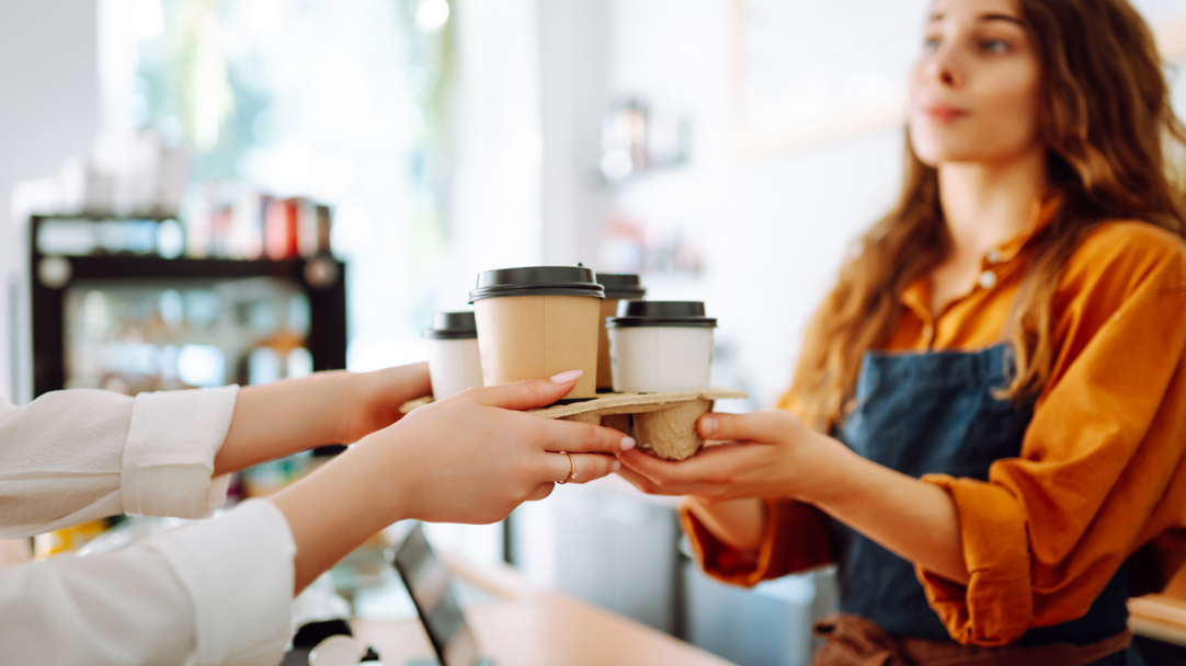 Barista handing over coffee to customer on a counter in a bar