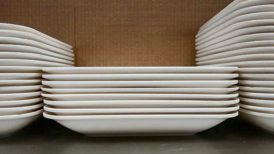 White Disposable plates stack on a black table on a brown background