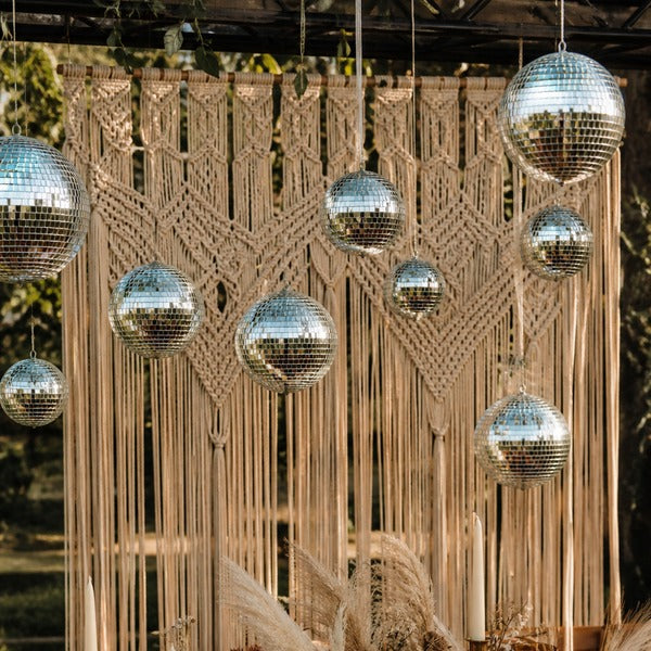 '70s-themed wedding décor with macramé backdrop, disco balls, and earth-tone table settings