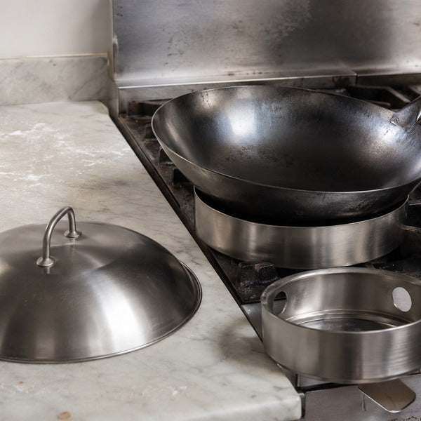 Restaurantware wok pan with wok ring and cover staged on a commercial range