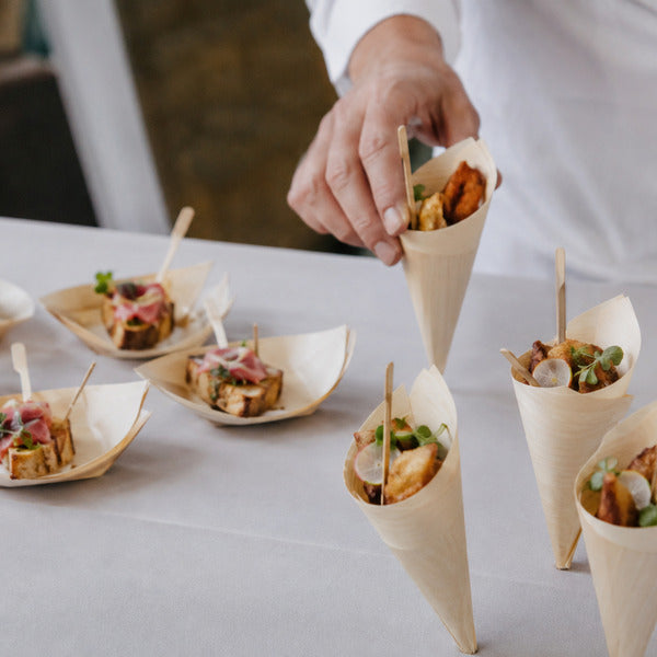 Catering appetizers served on bamboo tableware boats and cones at a foodservice event