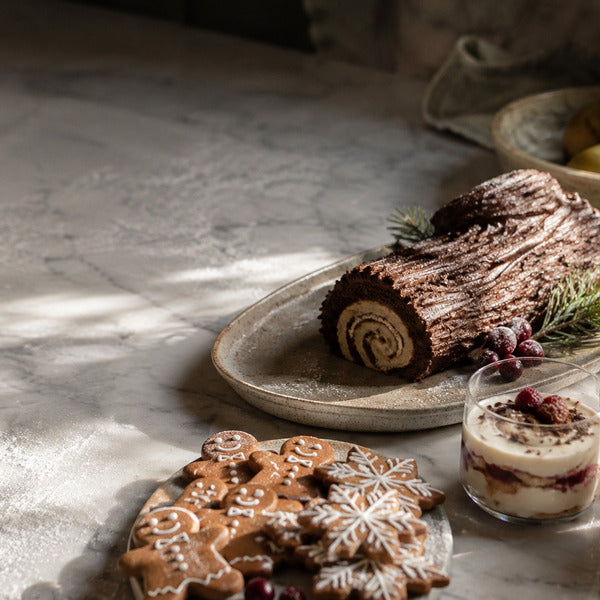 Christmas desserts on a restaurant dessert table with yule log, gingerbread cookies, and mini trifles