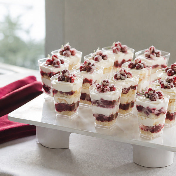 Individual Christmas desserts — mini cranberry trifles in clear cups on a catering display stand