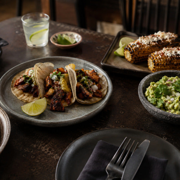 Cinco de mayo foods spread with tacos, guacamole, elote, and churros on a restaurant table