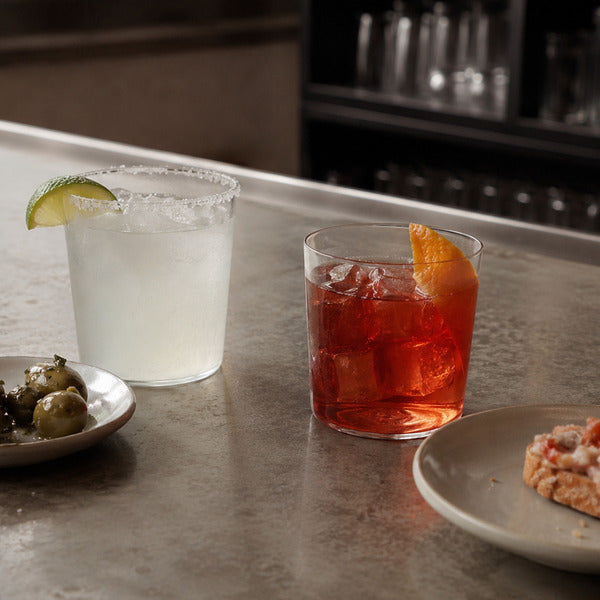 Popular cocktails paired with appetizers, showing a margarita and negroni with small plates