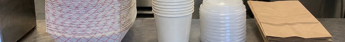 Concession stand supplies, including cups, lids and trays, are stacked at a service window during a high-volume event.