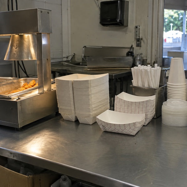 Concession stand setup showing the hold zone, stacked paper trays and cups staged toward the service window.