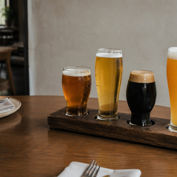 Flight showing what are the different types of beer — IPA, pilsner, stout, and wheat beer in style glasses