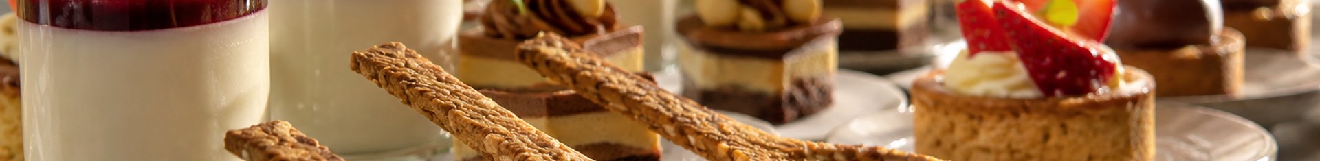 Edible cutlery spoons made from baked grain served alongside desserts at a catering event