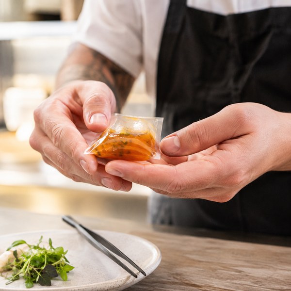 Chef demonstrating edible food packaging with a dissolvable starch film wrapper on a sauce portion