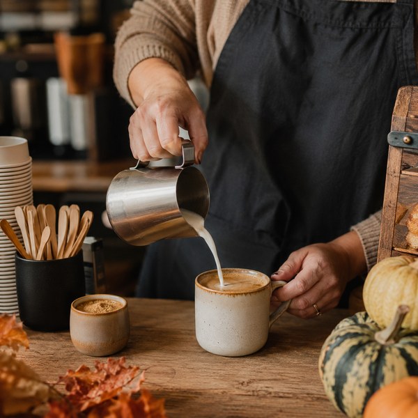 Barista sleeving insulated paper hot cups with kraft sleeves — fall coffee shop supplies in use