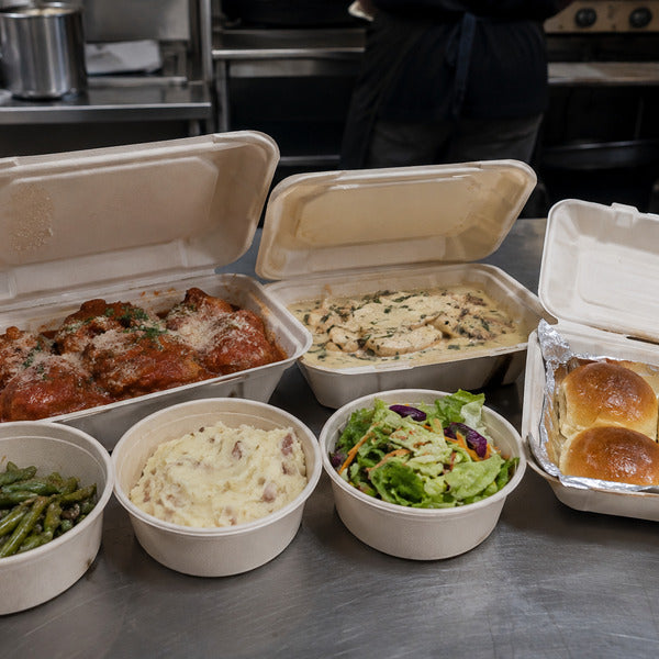 Restaurant family meal deals packed in to-go containers with entrée, sides, and bread for four