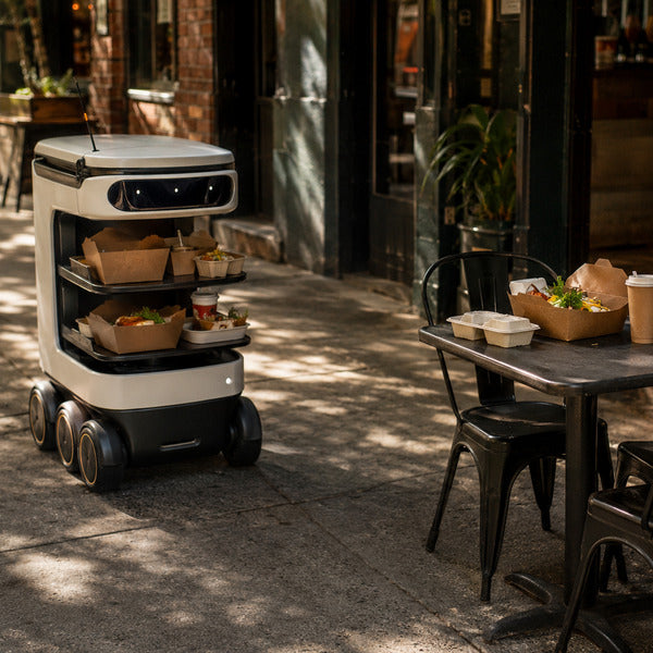 Autonomous food delivery robot carrying restaurant orders on a city sidewalk.