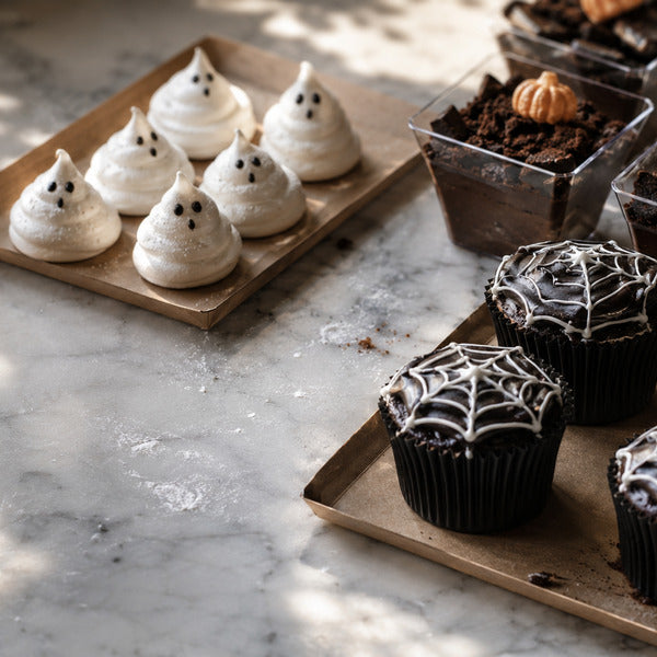 Assortment of Halloween desserts for foodservice including spiderweb cupcakes, dirt cups, and ghost meringues