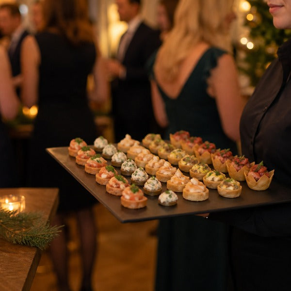 Server presenting passed appetizers on platters at a restaurant holiday party
