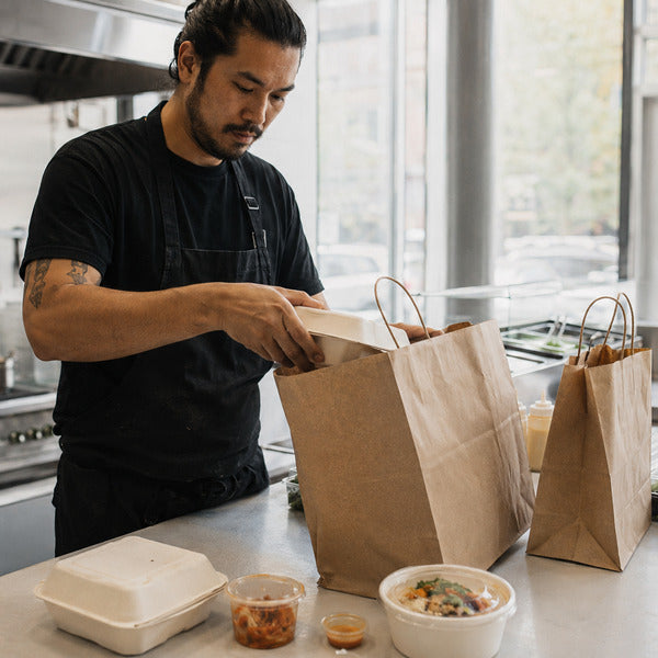 Chef packing a takeout bag at a ghost kitchen delivery station