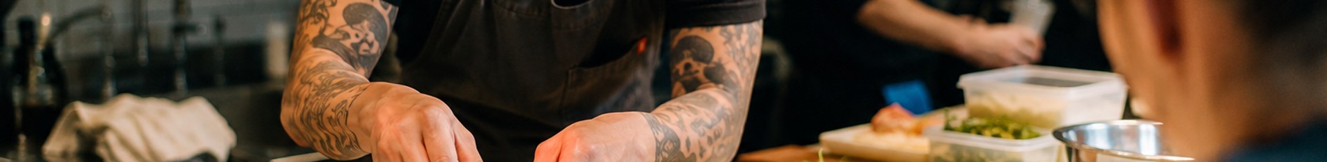 Chef plating dishes at a busy counter, showing how to start a pop-up restaurant service night