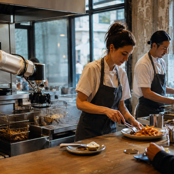Kitchen robot fry station working alongside staff in a commercial kitchen.