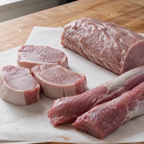 Leanest pork cuts including pork tenderloin, loin chops, and sirloin roast arranged on a butcher counter