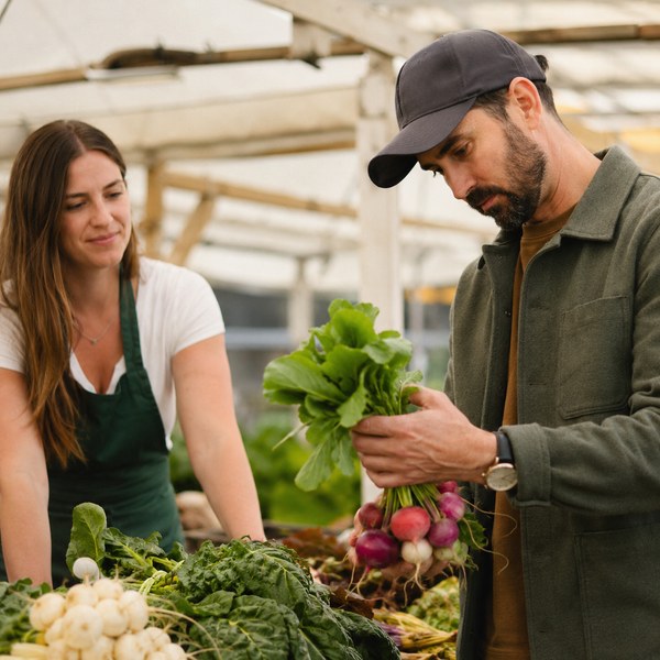 Restaurant buyer selecting seasonal local produce for restaurants at a farm stand