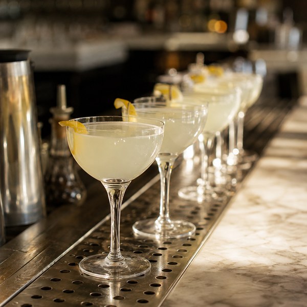 Nick and Nora glasses lined up on a commercial bar for corpse reviver cocktail service
