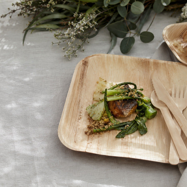 Palm leaf plates and wooden cutlery in an eco-friendly tableware wedding place setting