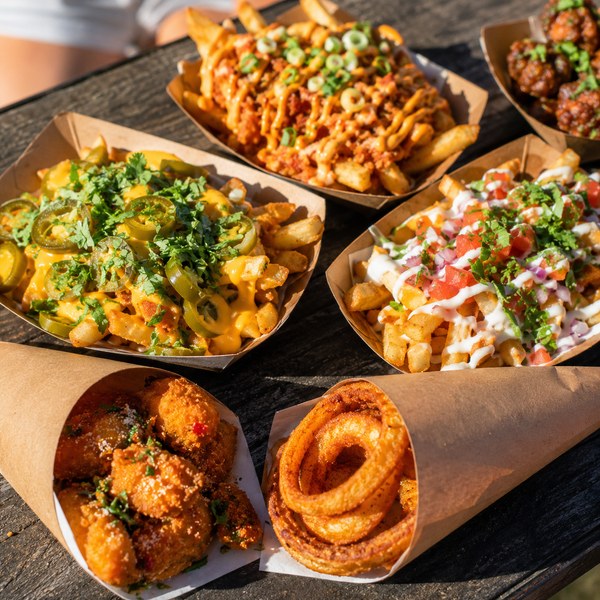 Paper food trays and food cones holding loaded fries and snacks — festival food ideas served one-handed