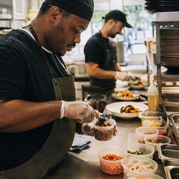 Kitchen staff using portion control cups to keep restaurant food costs consistent during food inflation