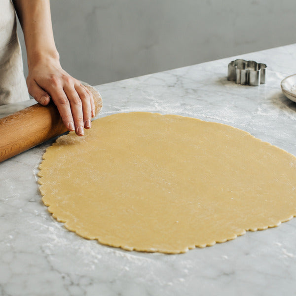 Rolling out chilled sugar cookie dough on a floured marble surface
