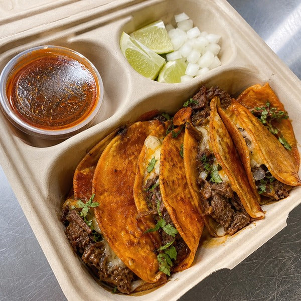 Quesabirria tacos packed in a compostable three-compartment taco take-out container with a sealed consommé cup