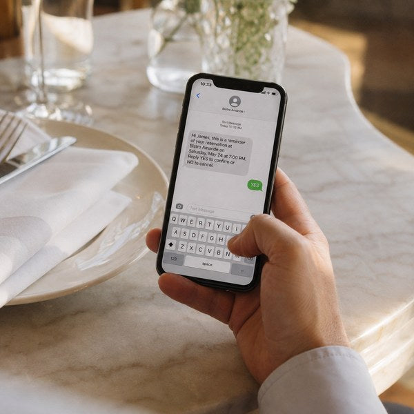 Guest confirming a restaurant reservation system reminder text next to a table setting