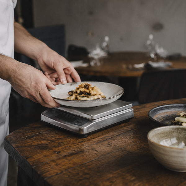 Kitchen staff using a portion scale to control food purchase costs and serving sizes