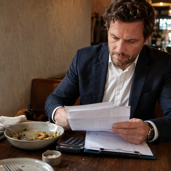 Restaurant manager comparing supplier invoices to cut food purchase costs during a quarterly audit