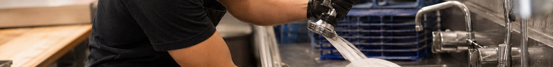 Restaurant water conservation in action: staff pre-rinsing dishes with a low-flow spray valve in a commercial kitchen