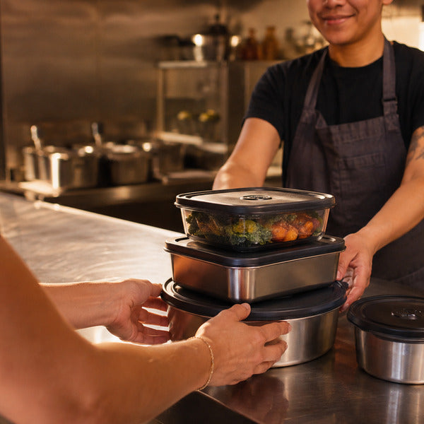 Stack of reusable food containers being returned at a restaurant counter for a reuse program