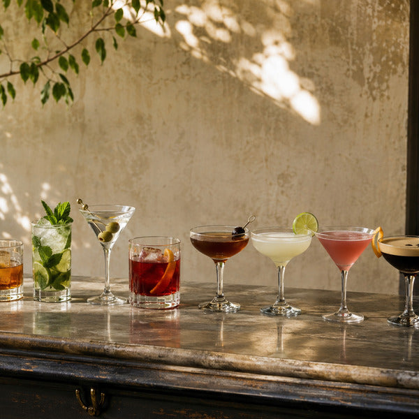 The 10 most popular cocktails lined up on a bar, including margarita, old fashioned, and mojito